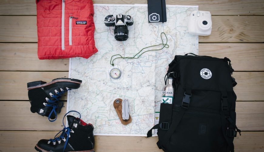 A backpack, hiking boots, and a camera arranged on a map, symbolizing adventure for family holiday packages in Kenya.